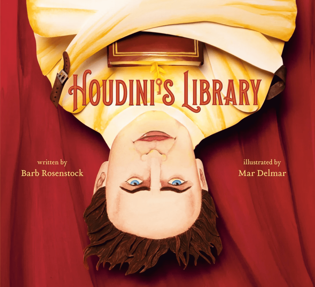 Cover image for Houdini’s Library: How Books Created the World’s Greatest Magician by Barb Rosenstock, illustrated by Mar Delmar. Featuring Houdini hanging upside down in a straightjacket holding a book.