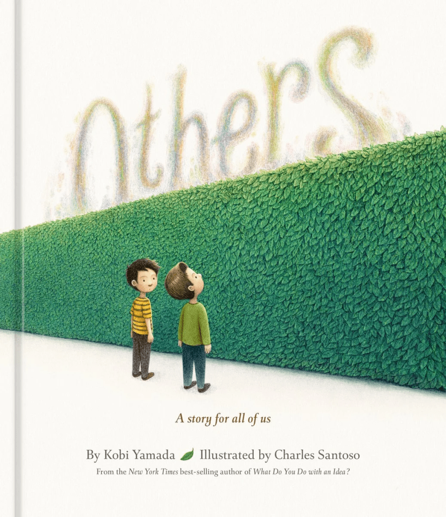 Cover image for Others: A Story for All of Us by Kobi Yamada, illustrated by Charles Santoso, featuring two boys standing near a large green hedge that runs across the cover.
